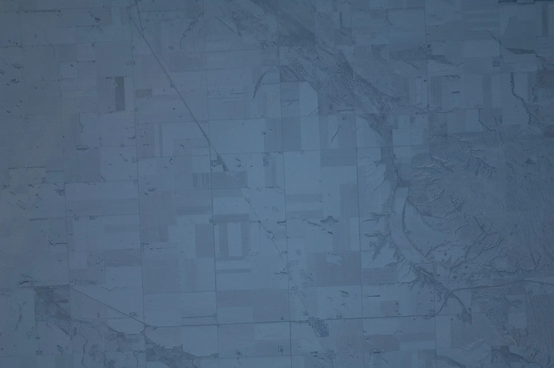 Aerial view of snowy farmland and valley from space